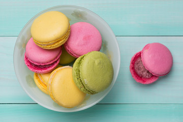 multicolored macarosa or marshmallows in a plate on green wooden boards, macaros lie side by side on boards