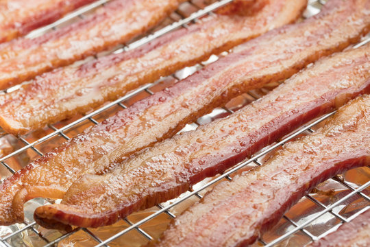 Rows of fried bacon strips on a baking sheet