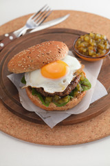 Hamburger with fried egg and gherkin salad