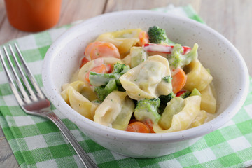 Tortellini with vegetables under cream sauce