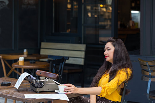 Writer female working in a coffee shop using a retro typewriter
