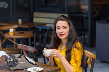 Fototapeta na wymiar Writer female working in a coffee shop using a retro typewriter