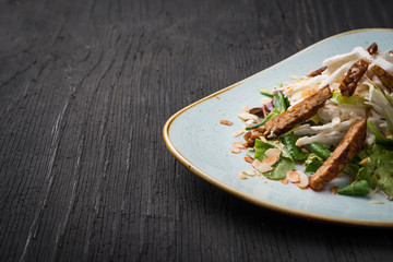 Vegan salad with goat cheese and nuts in plate over rustic table