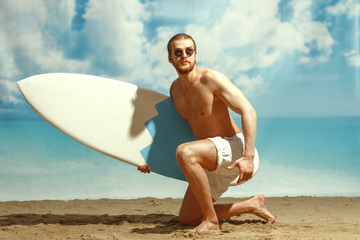 A man with a surfboard in his hands on the sandy beach.
