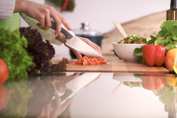 Close Up of human hands cooking vegetable salad in kitchen on the glass table with reflection. Healthy meal, and vegetarian food concept