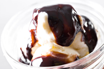 Vanilla ice cream with chocolate syrup on white background. Scoops of vanilla ice cream in glasses bowl.