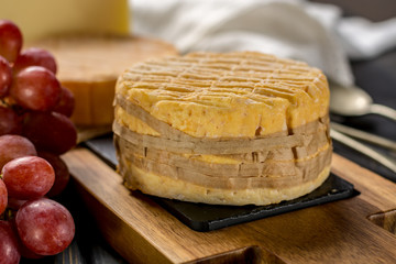 Tasting of oldest french AOC soft pudgent wrapped yellow cheese Livarot from Normandy, french cheese