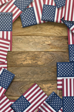 small United States flags framing a wood texture background with copy space