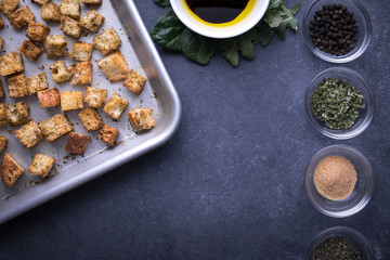Flay lay of croutons on a baking sheet, beside recipe ingredients and space for text on bottom