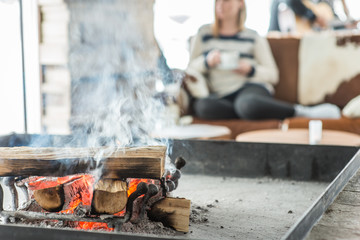 Unrecognizable woman drinkin tea next to fireplace;