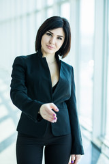 Pretty business Woman shaking hands against panoramic window