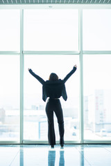 Fototapeta na wymiar Confident businesswoman spreading hands standing at office window, enjoying big city, successful entrepreneur celebrating business success with arms open wide, feeling powerful inspired, rear view