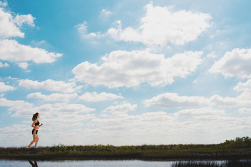 Obraz premium Running girl on a green field and bright sky