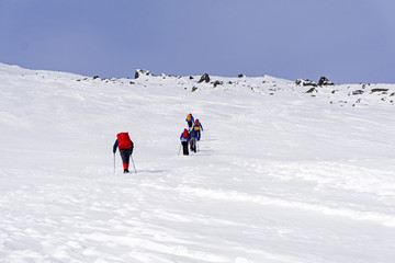 Fototapeta na wymiar group of hikers on snow-covered mountain slope under a bright blue sky