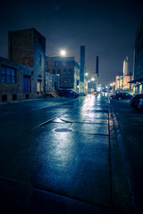 Obraz premium Foggy industrial urban street city night scenery in Chicago with vintage warehouses, factories and smokestacks after a rain.