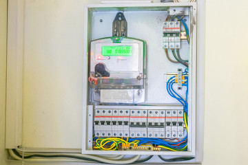 The electricity meter is in the electrical box. Electric cabinet with wires and circuit breakers. Electricity counter coupled to automatic switches. Cabling in the office