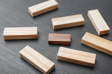 One wooden block standing out from others on dark background. Think different concept