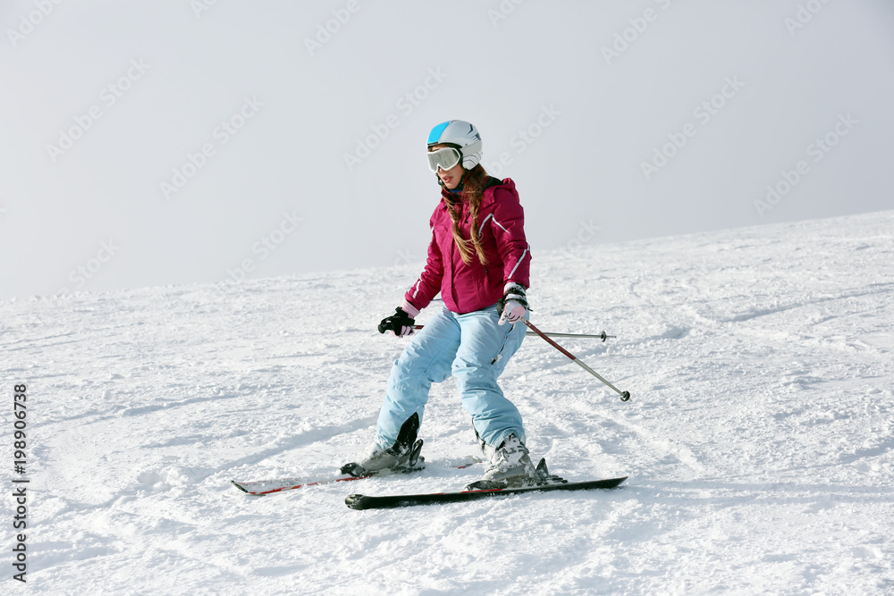 Poster Woman skiing on piste at snowy resort. Winter vacation