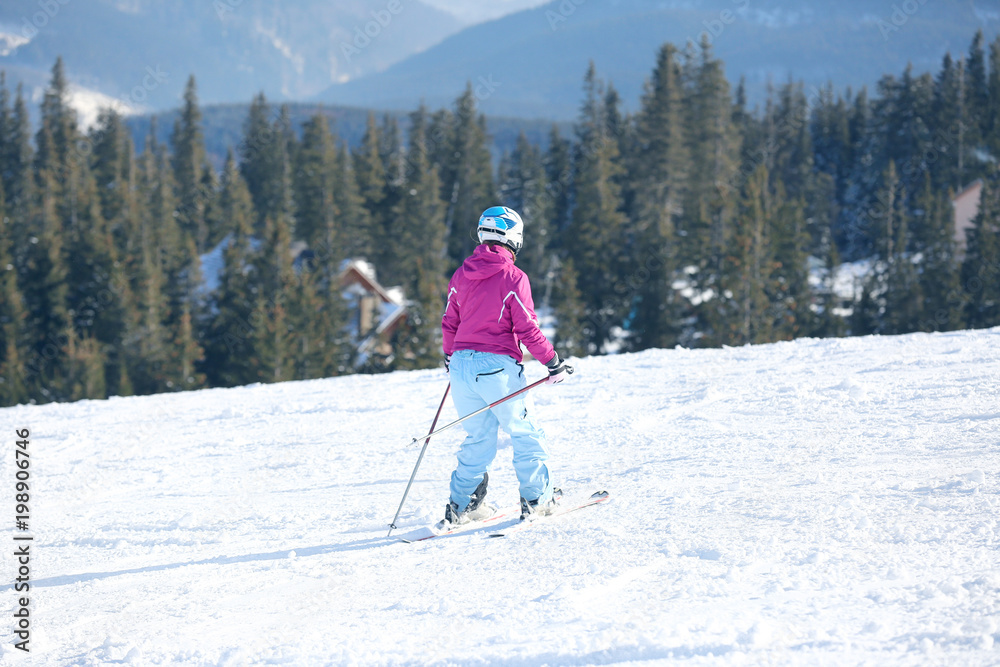 Poster Woman skiing on piste at snowy resort. Winter vacation