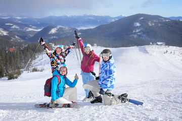 Happy friends on ski piste at snowy resort. Winter vacation