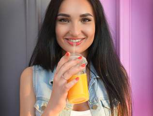 Healthy lifestyle. The brunette girl drinks fresh juice through a straw. Widely open eyes. Orange fresh. Vitamins. Surprise. Close-up portrait. Delicious.