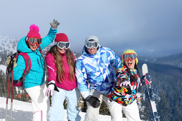 Happy friends on ski piste at snowy resort. Winter vacation