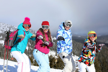 Happy friends on ski piste at snowy resort. Winter vacation