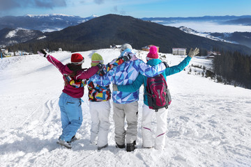 Happy friends on ski piste at snowy resort. Winter vacation