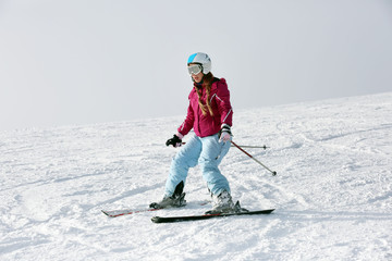 Fototapeta na wymiar Woman skiing on piste at snowy resort. Winter vacation