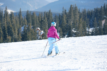 Fototapeta na wymiar Woman skiing on piste at snowy resort. Winter vacation