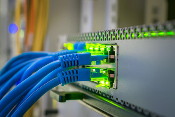 Bunch of patchcords are connected to a managed switch. Internet connection. Network wires are included in the ports of the central router. Selective focus