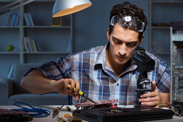 Repairman trying to repair laptop with miscroscope