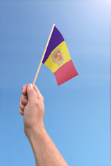 Hand holding a flag of Andorra on a bright sunny day