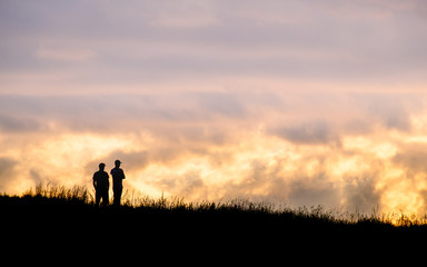 Obraz na płótnie Canvas Silhouette scene of a couple enjoy with their drone at sunset on the top of Mt. Eden, Auckland, New Zealand.