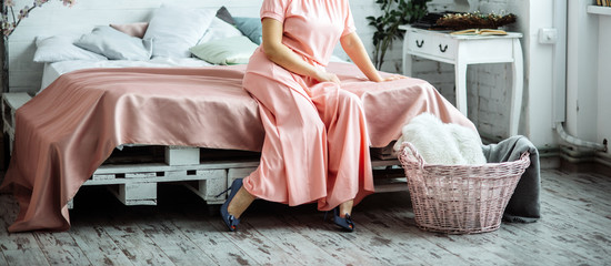beautiful woman is sitting on the bed in elegance dress