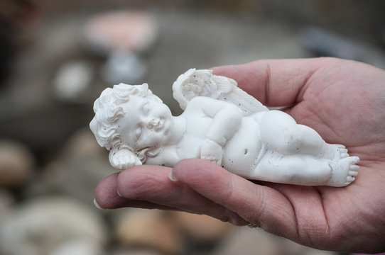 Closeup of stoned angel in hand of woman in cemetery