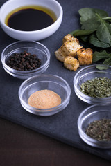 Croutons beside glass ingredient dishes of spices