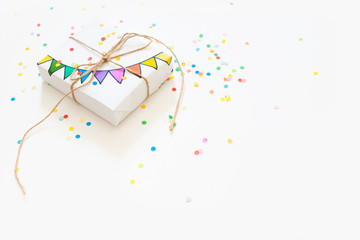 White gift box. Drawing of a colored garland, flags. White background. Confetti.
