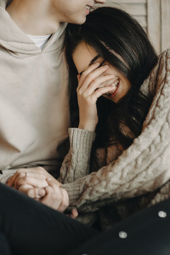 Girl staying in her boyfriend's arms , smiling and covering her face with her hand.