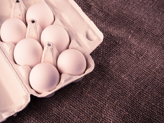 Open packing with white eggs on an old wooden background