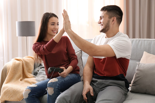 Young couple sitting on sofa and playing video game at home