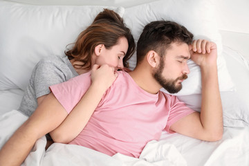 Husband and wife sleeping in bed at home