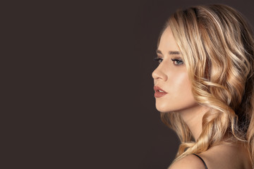 Beautiful young woman with long wavy hair on color background
