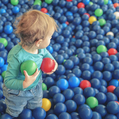 Fototapeta na wymiar happy little child plays on a playground filled with colorful plastic balls.