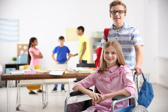 Boy helping girl in wheelchair at school