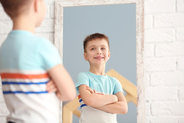 Cute little boy posing in front of mirror indoors