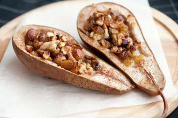 Dessert from the baked pears with honey and nuts in a wooden plate