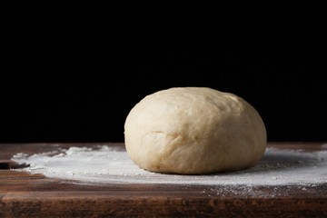 Pizza dough or baking on a dark black background of wood. Baking bread, pizza, pasta. Recipe from chef cooks pizza. Italian home cooking. Copy space, horizontal photo