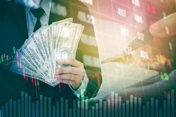 Businessman Holding money US dollar bills on digital stock market financial exchange information...