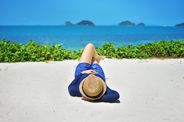 Woman laying on white sand  in beach  hat enjoying summer holidays